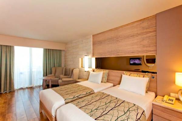 Doppelzimmer im Melas Resort mit zwei Betten, Holzwänden und einem Fernseher.