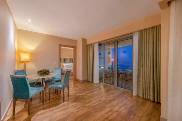 Essbereich im Melas Resort mit runden Tisch und blauen Sesseln vor einem großen Fenster