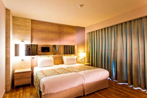 Doppelbett-Zimmer im Melas Resort mit blauen Vorhängen und Holzboden.