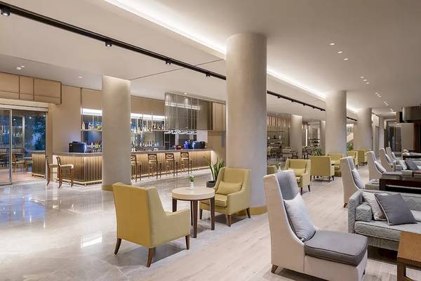 Lobby-Bereich des Melas Resorts mit Sitzbereichen, Bar und hoher Decke.