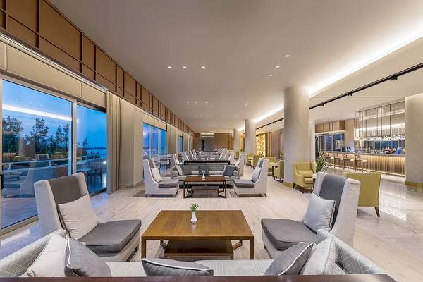 Lobbybereich des Melas Resorts mit Sitzbereichen, Tischen und einer Bar.