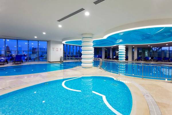 Innenpoolbereich des Melas Resorts mit blauen Wänden und Säulen, gefüllt mit klarem Wasser.