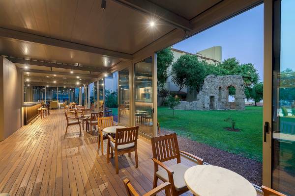 Terrasse des Melas Resorts mit Blick auf Ruinen und grüne Rasenfläche