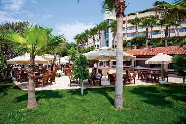 Außenbereich des Melas Resorts mit Tischen, Stühlen und Sonnenschirmen im Freien.