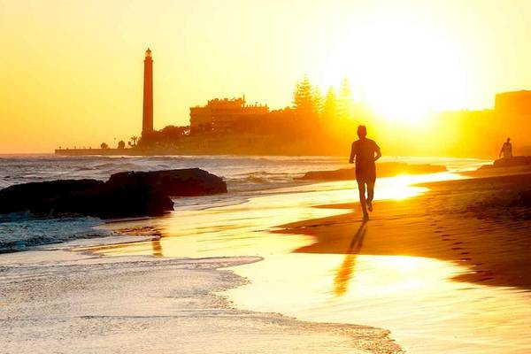 Person läuft auf dem Strand neben dem Europalace Hotel bei Sonnenuntergang
