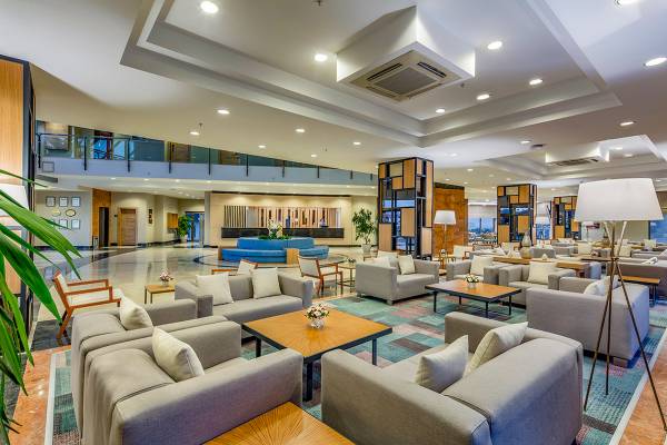 Lobby des Novum Garden Side Hotels mit Sitzbereichen, Tischen und Blumenarrangements.
