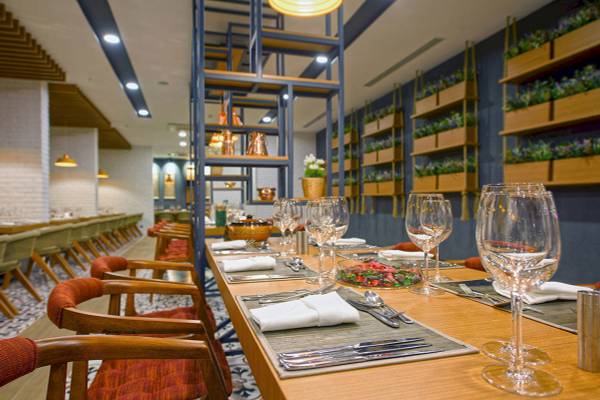 Speisesaal des Novum Garden Side Hotel mit gedeckten Tischen und Pflanzen an der Wand.