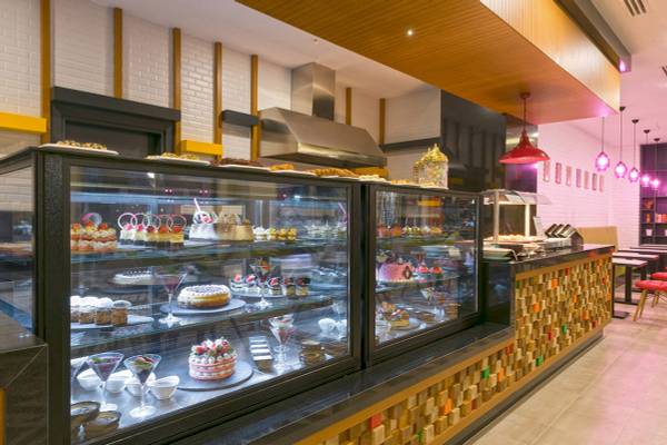 Innenansicht des Cafés im Novum Garden Side Hotel mit Vitrinen voller Kuchen und Desserts.