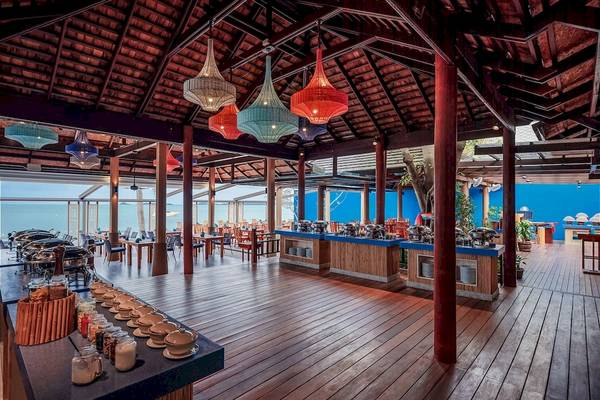 Innenansicht des Restaurants im Bandara Resort & Spa, Samui, mit Holzboden, blauen Wänden und Meeresblick.