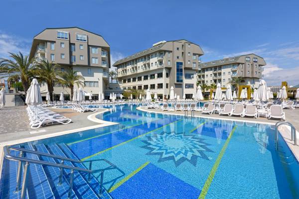 Ein großer Swimmingpool im Freien mit weißen Sonnenliegen und Schirmen vor dem Novum Garden Side Hotel.
