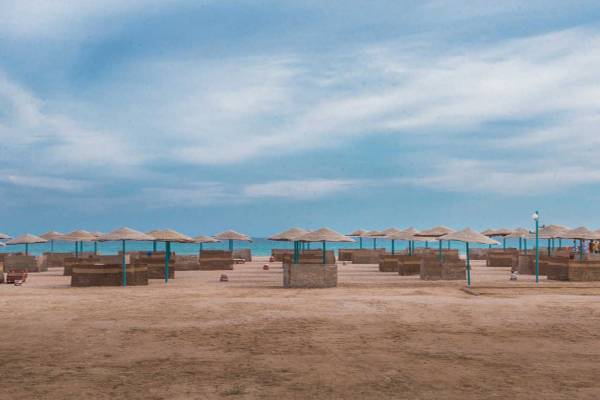 Eine Strandszene mit vielen Strohhütten und Sonnenschirmen am Meer