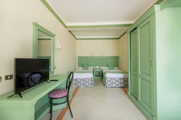 Zimmer im Shams Safaga Resort mit zwei Betten, grünen Möbeln und einem Fernseher.