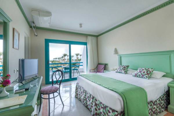 Hotelzimmer im Shams Safaga Resort mit grünem Bett, Fernseher, Schreibtisch und Balkon