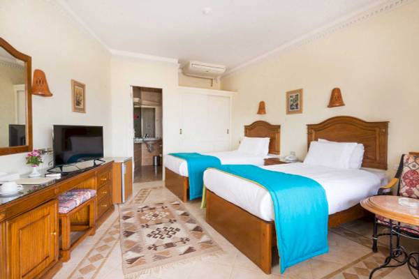 Doppelzimmer im Shams Safaga Resort mit zwei Betten, Fernseher, Badezimmerzugang und Dekor.