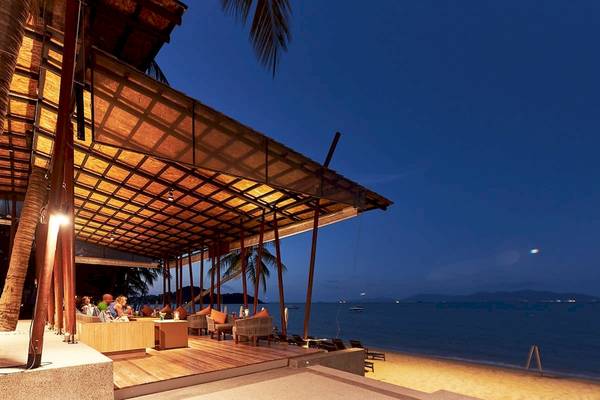Abendlicher Außenbereich des Bandara Resort & Spa mit Loungestühlen und Tischen am Meer