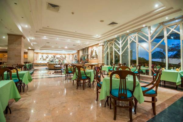 Innenansicht des Restaurants im Shams Safaga Resort mit grün gedeckten Tischen und Stühlen.