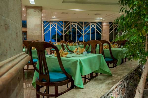Innenansicht des Restaurants im Shams Safaga Resort mit grün gedeckten Tischen und blauen Stühlen.
