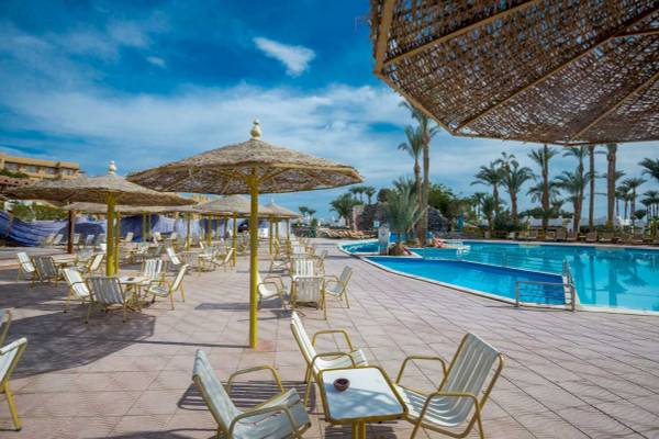 Außenbereich des Shams Safaga Resorts mit Swimmingpool, Sonnenschirmen und Stühlen.