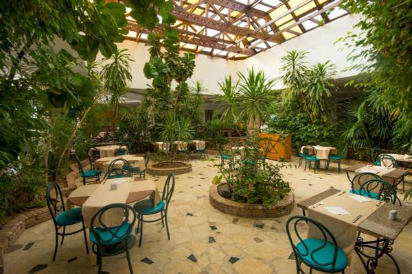 Gartenrestaurant im Shams Safaga Resort mit üppigem Grün und runden Tischen.
