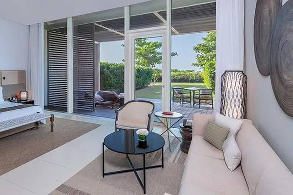Suite-Innenansicht im Oberoi Beach Resort, Al Zorah mit Bett, Sofa und Terrassenzugang