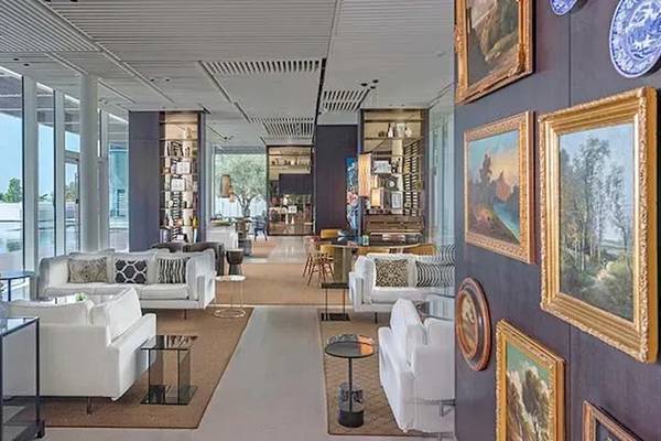 Lobby des Oberoi Beach Resort in Al Zorah mit weißen Möbeln und Gemälden an der Wand.