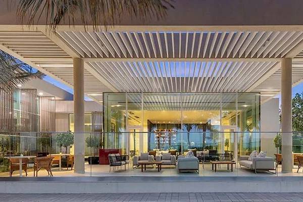 Außenbereich des Oberoi Beach Resort Al Zorah mit Glasfassade und Möbeln.