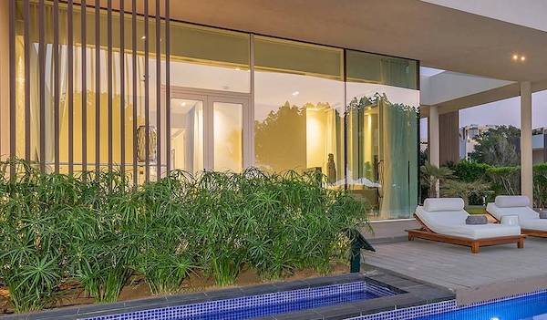 Außenbereich des Oberoi Beach Resort Al Zorah mit Swimmingpool und Lounges