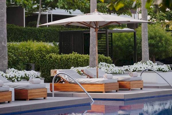Pool-Loungebereich im Oberoi Beach Resort mit Sonnenliegen und einem großen Sonnenschirm.