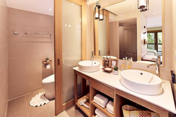Badezimmer im Bandara Resort & Spa, Samui mit zwei Waschbecken, Toilette und Spiegel.