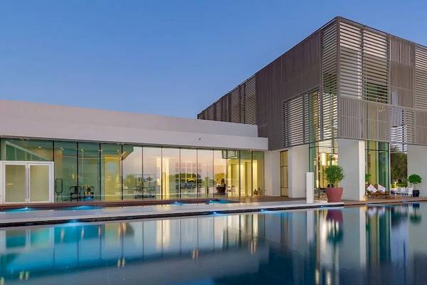 Außenansicht des Oberoi Beach Resort Al Zorah mit großem Pool und modernem Gebäudedesign.