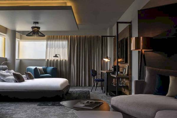 Hotelzimmer im Novotel London Canary Wharf mit Bett, Sofa, Schreibtisch und Fenstern.