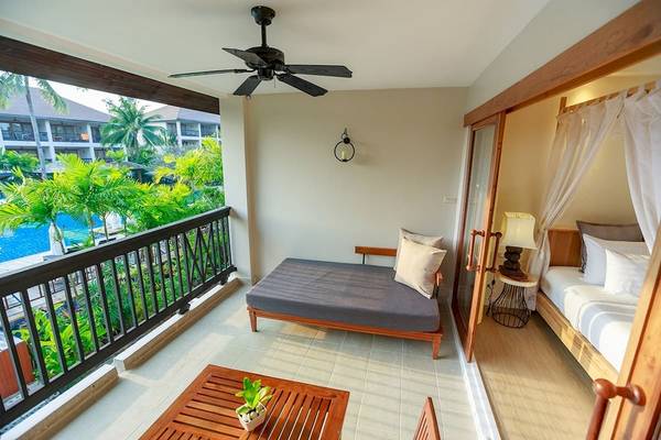 Balkonansicht eines Zimmers im Bandara Resort & Spa, Samui, mit Tagesbett, Tisch und Blick auf den Pool.