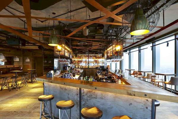 Innenansicht der Bar im Novotel London Canary Wharf Hotel mit Holztheke und Barhockern.