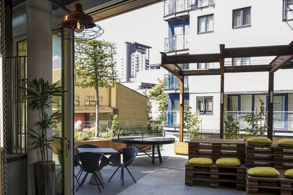 Blick auf den Außenbereich des Novotel London Canary Wharf Hotels mit Tisch, Stühlen und Pflanzen.