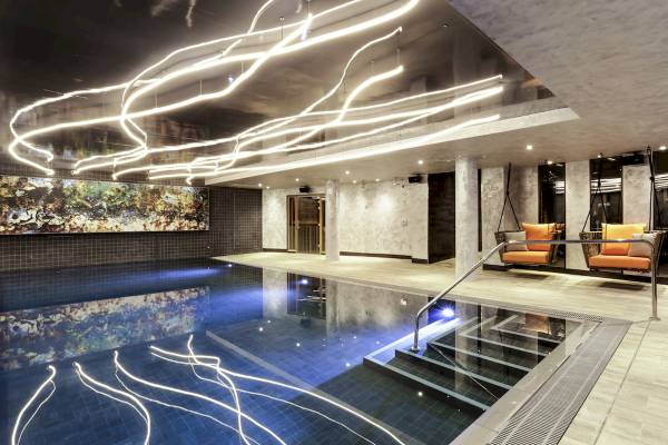Indoorpool im Novotel London Canary Wharf mit blauem Wasser und leuchtenden Lichtern an der Decke.