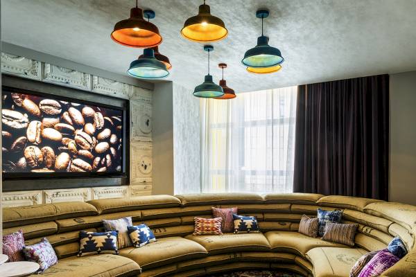 Lobby-Lounge des Novotel London Canary Wharf mit großer Couch und Kaffeebohnen-Bildschirm.