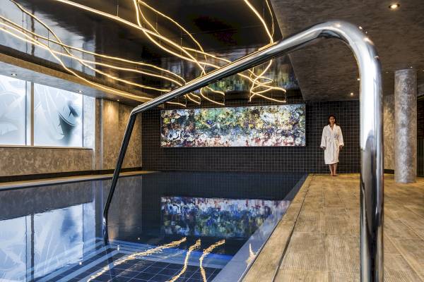 Novotel London Canary Wharf Innenpool mit moderner Beleuchtung und Kunstwerk an der Wand.