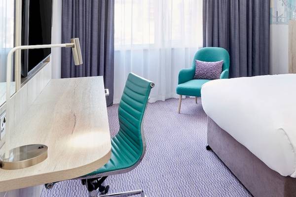 Leonardo Hotel London Croydon Zimmer mit Bett, Schreibtisch und Stühlen.