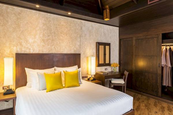 Schlafzimmer im Bandara Resort & Spa, Samui mit weichen weißen und gelben Kissen.