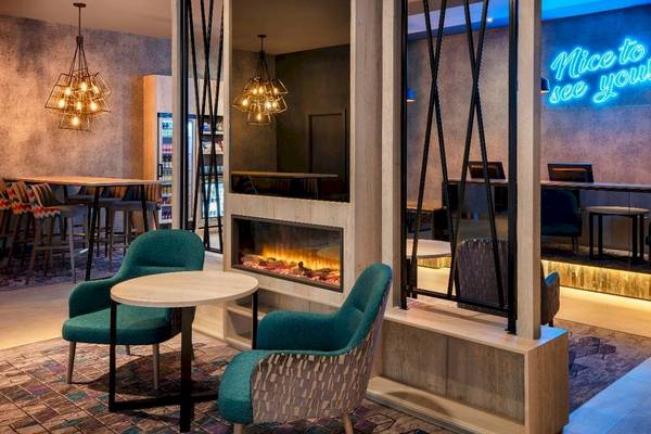 Leonardo Hotel London Croydon Lobby Lounge mit Kamin, grünen Stühlen und Schreibtischen.