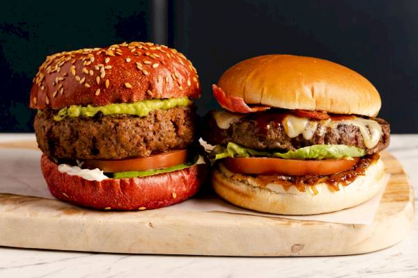 Zwei Burger mit verschiedenen Toppings auf einem Holzschneidebrett