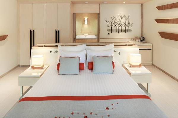 Schlafzimmer im Bandara Resort & Spa, Samui mit Bett, Kissen, Nachttischen und Wanddekoration.