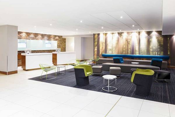Lobby-Bereich des Novotel London West mit Möbeln und einer großen Wandgrafik.
