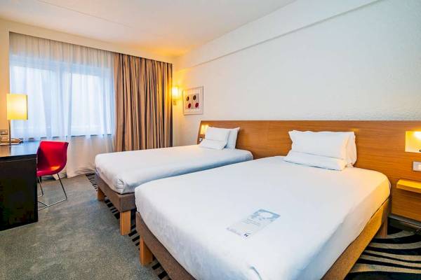 Doppelzimmer im Novotel London West mit zwei Betten, Schreibtisch und Fenstern.