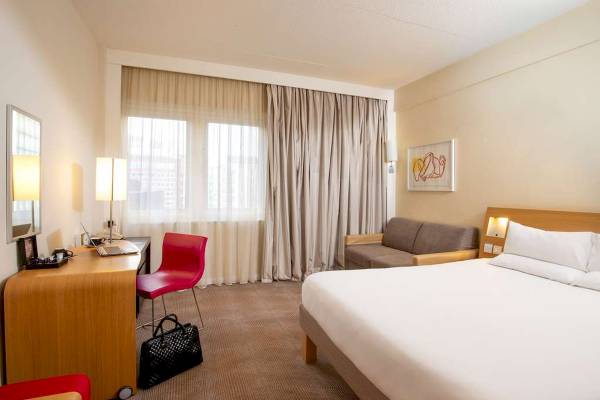Hotelzimmer im Novotel London West mit Bett, Schreibtisch und Sofa.