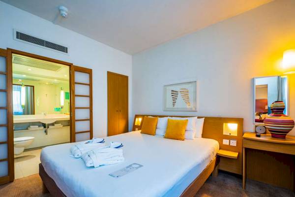 Ein elegantes Schlafzimmer im Novotel London West Hotel mit einem großen Bett, Dekor und Möbeln.