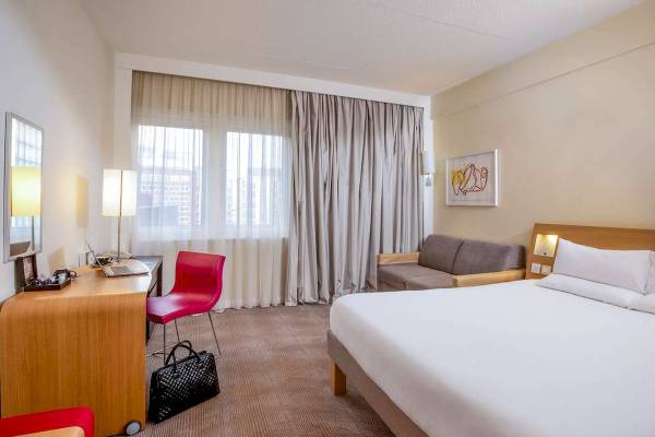 Hotelzimmer im Novotel London West mit Schreibtisch, Laptop, roter Stuhl und Sofa