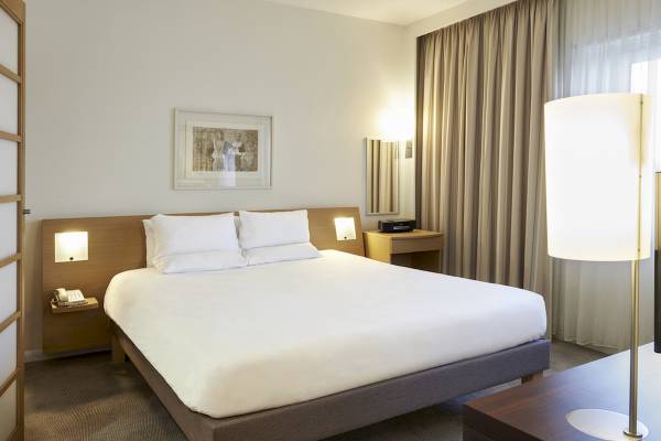 Doppelbettzimmer im Novotel London West Hotel mit weißem Bett, Nachttischen und Lampen.