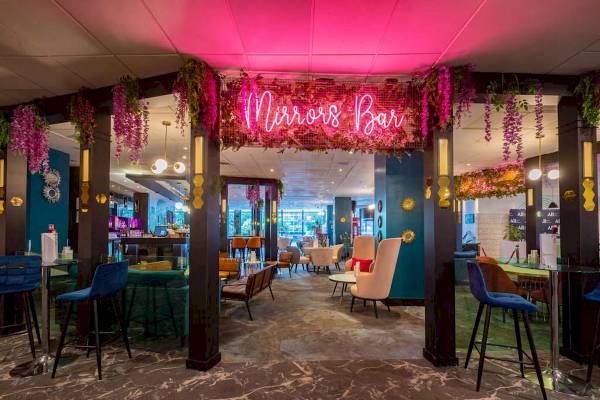 Innenansicht der Mirrors Bar im Novotel London West mit bunten Neonleuchten und farbenfrohem Dekor.