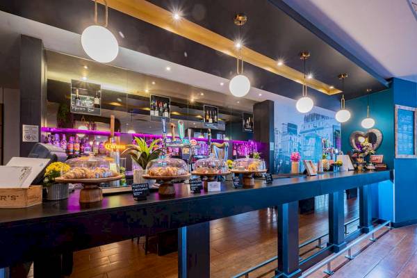 Innenansicht der Bar im Novotel London West Hotel mit Theke, Croissants, Blumen und Dekor.
